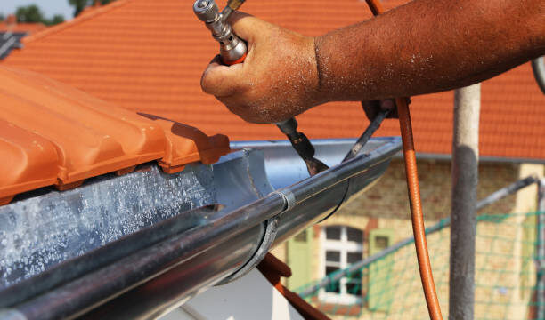 Roofer doing plumbing work on a gutter